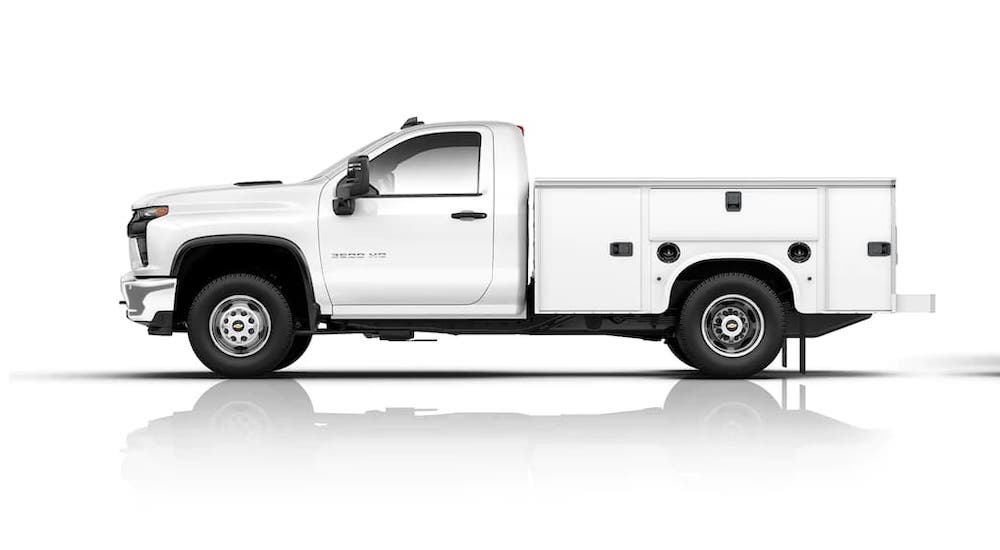 A white 2021 Chevy Silverado 3500 HD Chassis Cab with a utility bed is shown from the side on a white background.