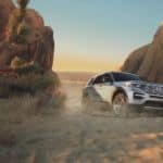 A silver 2021 Ford Explorer is driving between two rock formations in a desert.