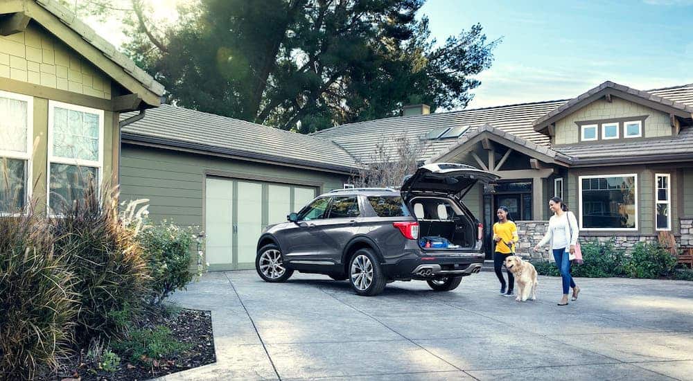 A family and dog are getting into a gray 2021 Ford Explorer which is parked in a driveway.