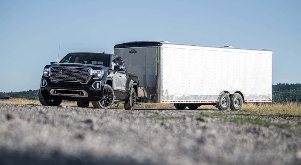 A black 2021 GMC Sierra 1500 Denali is towing a large white enclosed trailer.