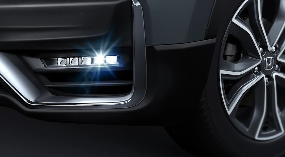 A close up is shown of the fog light and wheel on a dark grey 2021 Honda CR-V Hybrid.