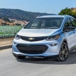 A classic Chevy EV, a silver 2021 Chevy Bolt EV, is driving around a field.