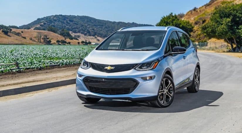 A classic Chevy EV, a silver 2021 Chevy Bolt EV, is driving around a field.