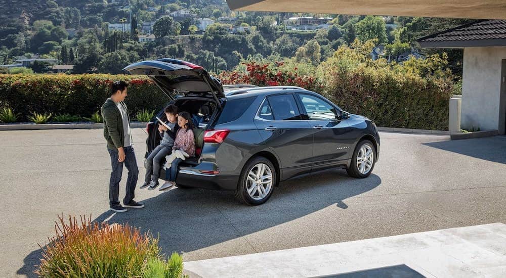 A dark gray 2021 Chevy Equinox is shown from behind with a man and two children.