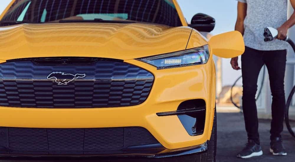 Someone is about to plug in a yellow 2021 Ford Mustang Mach-E.