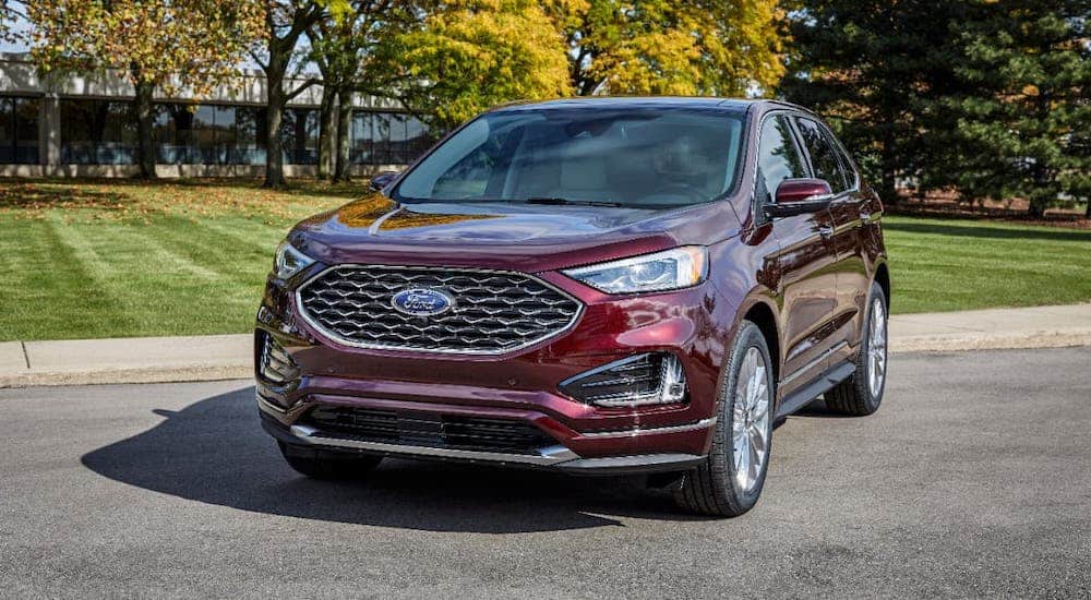 A red 2021 Ford Edge is parked in front of grass and trees.