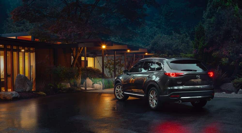 A gray 2021 Mazda CX-9 is shown from behind with its lights on at night.