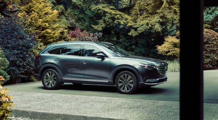 A gray 2021 Mazda CX-9 is shown from the side parked on a driveway.