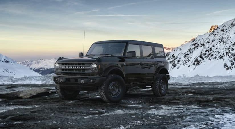 A black 2021 Ford Bronco 4-door Black Diamond is parked on a snowy mountain after leaving a NY Ford Bronco dealer.