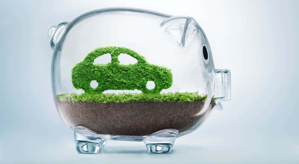 A glass piggy bank is shown with a green car inside.