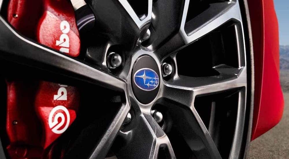 A close up shows a wheel and red performance caliper is shown on a red 2021 Subaru WRX.