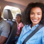 A happy family is sitting in a car after leaving a used car dealer.
