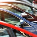 A row of cars is shown on a used car dealer lot.