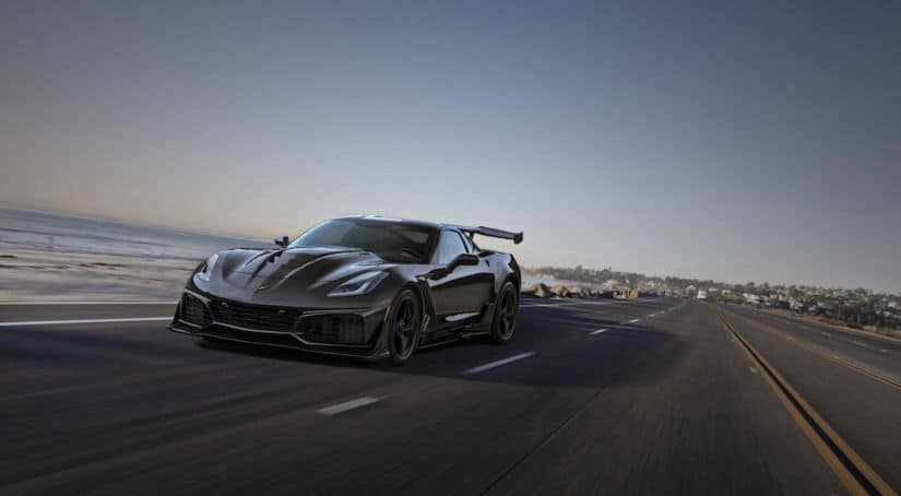 A black 2019 Chevy Corvette ZR1 is driving down a coastal raod after leaving a used Chevy dealer.