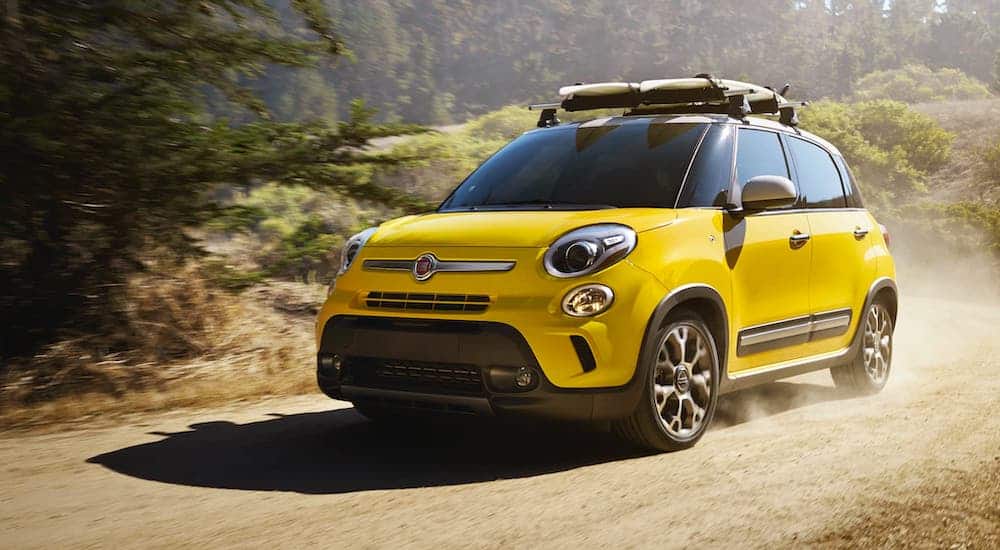 A yellow 2015 Fiat 500X is driving on a dirt road.