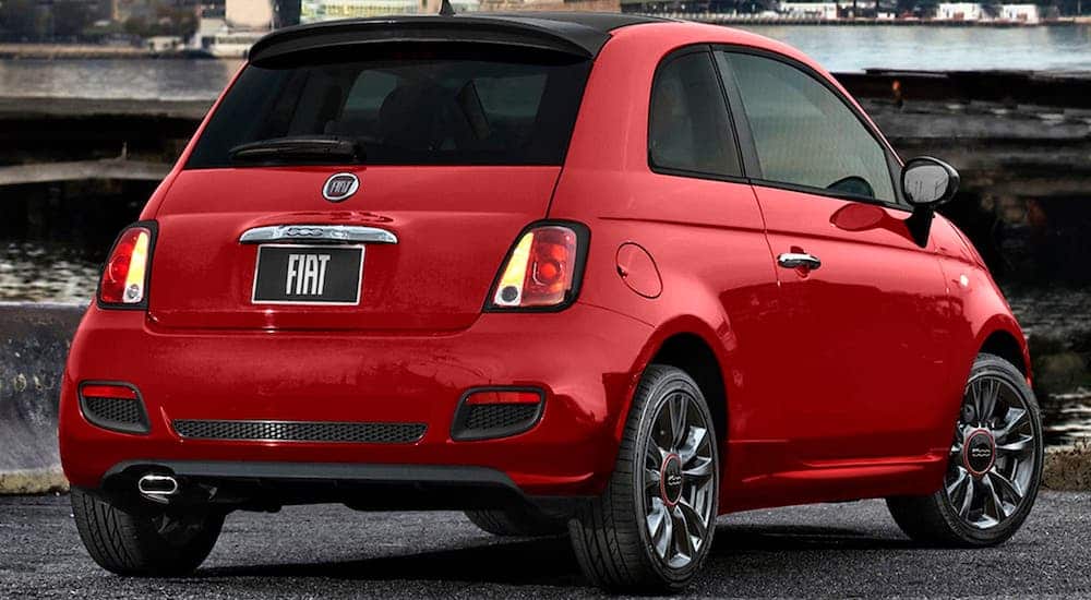 A red 2017 Fiat 500 is shown from the rear parked in front of a waterfront.