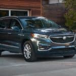 A dark gray 2021 Buick Enclave Avenir is parked in front of a garage.