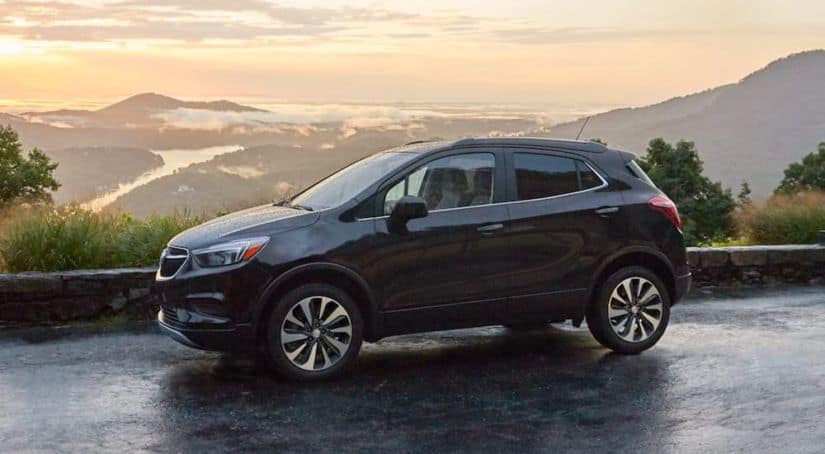 A black 2021 Buick Encore is parked in front of a mountain lookout at sunset.