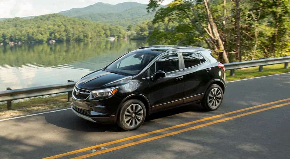 A black 2021 Buick Encore is driving past a pond.