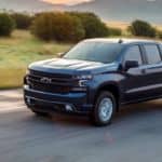 A blue 2021 Chevy Silverado 1500 RST is driving on a rural road after winning the 2021 Chevy Silverado 1500 vs 2021 GMC Sierra 1500 comparison.