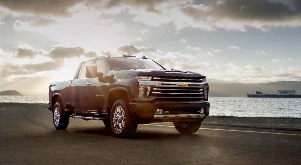 A black 2021 Chevy Silverado 2500 HD High Country is parked in front of a river and a large ship.