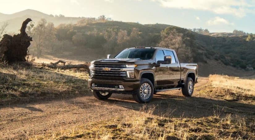 A black 2021 Chevy Silverado 2500 HD High Country is parked on a dirt trail with yellow grass.