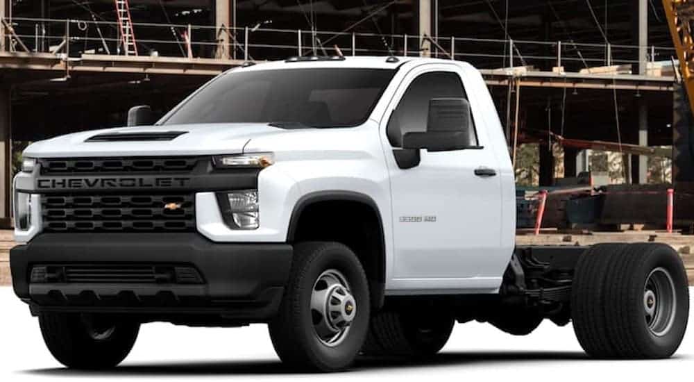 A white 2021 Chevy Silverado 3500 HD Chassis Cab with no bed is parked in front of a job site.