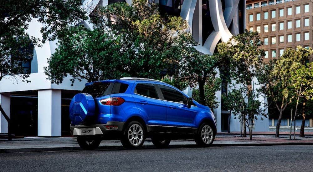 A blue 2021 Ford EcoSport is shown from a rear angle driving in a city.