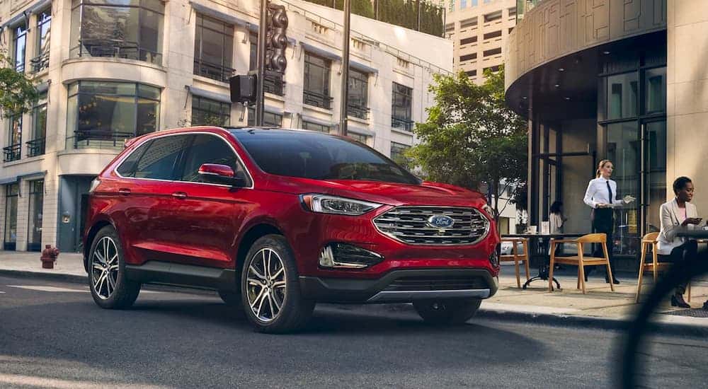 A red 2021 Ford Edge is parked on a city street with a restaurant in the background.