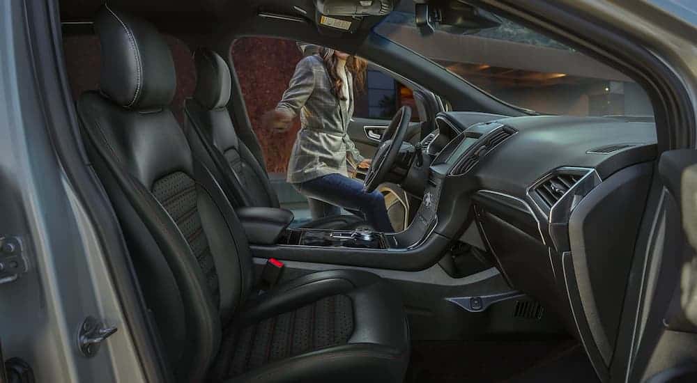 A woman getting in a 2021 Ford Edge is shown through the passenger side.