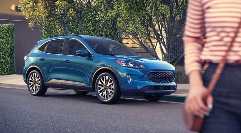 A blue 2021 Ford Escape is shown from the side parked on the street, with a woman in the foreground.
