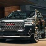 A man in a suit is shown opening the door of a black 2021 GMC Acadia Denali.