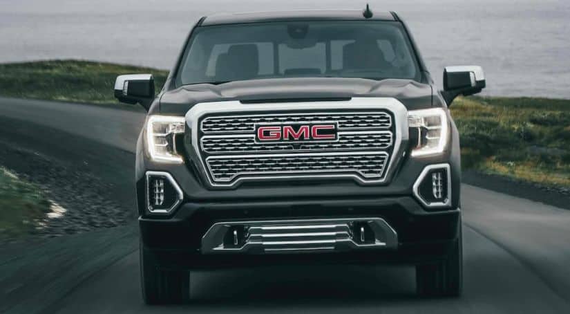 A dark gray 2021 GMC Sierra 1500 is shown from front driving away from a lake.