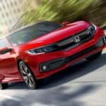 A red 2021 Honda Civic is shown on a angle on a city street after winning the 2021 Honda Civic vs 2021 Nissan Sentra comparison.