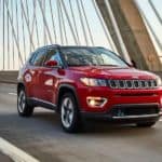 A red 2021 Jeep Compass is driving over a cable bridge.
