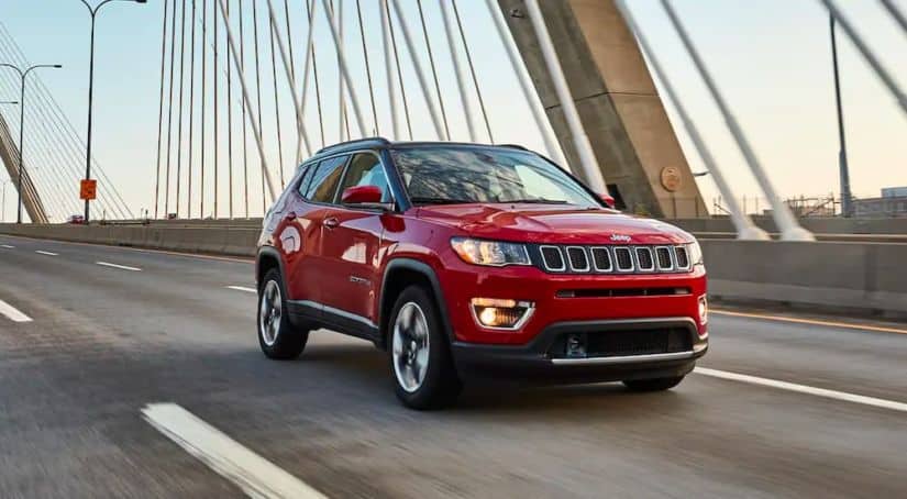 A red 2021 Jeep Compass is driving over a cable bridge.