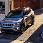 A gray 2021 Jeep Compass is shown from a high angle driving out of an alley.