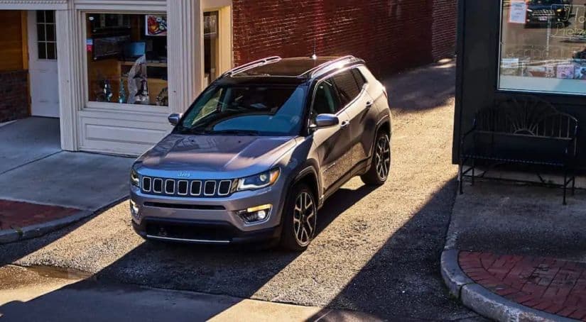 A gray 2021 Jeep Compass is shown from a high angle driving out of an alley.