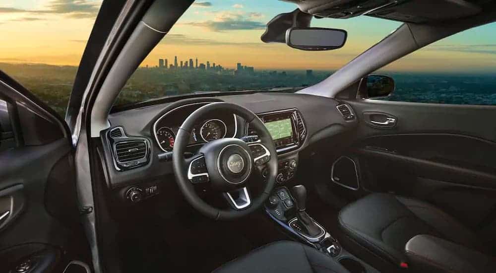 The steering wheel and interior of a 2021 Jeep Compass are shown through the driver's side door.