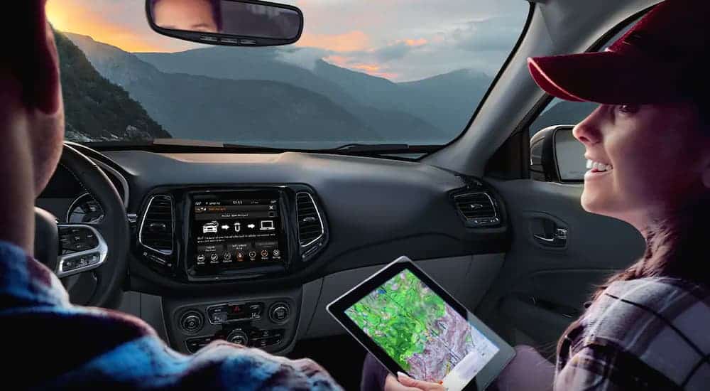 A couple is shown in a 2021 Jeep Compass overlooking a mountain range.