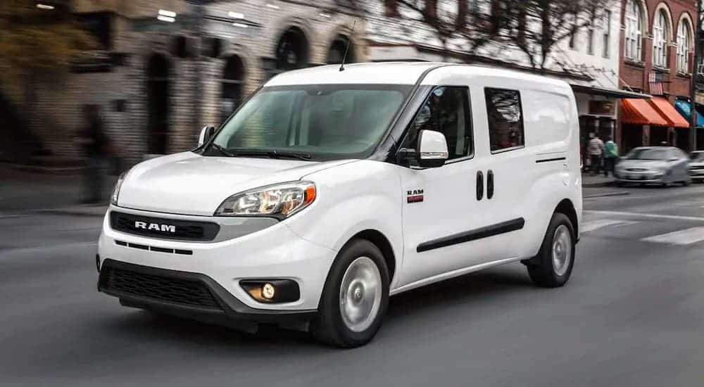 A white 2021 Ram ProMaster City van is driving on a city street.