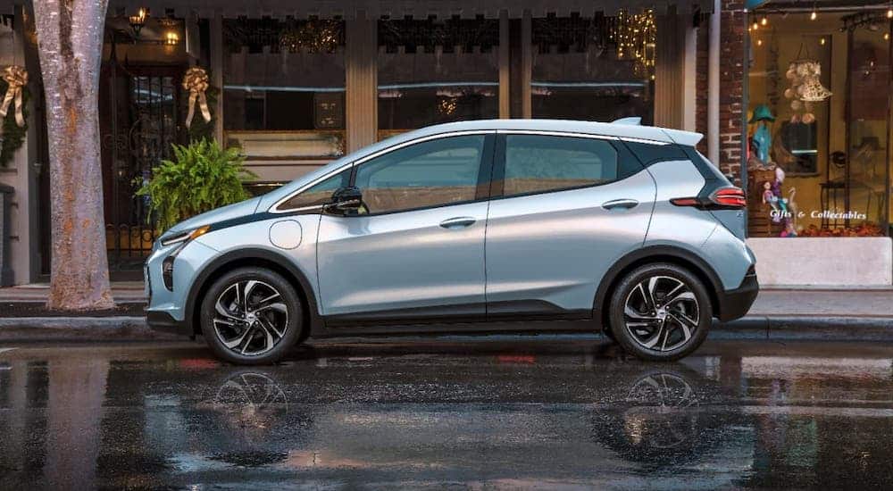 A pale blue 2022 Chevy Bolt EUV is shown from the side while parked in front of shops.