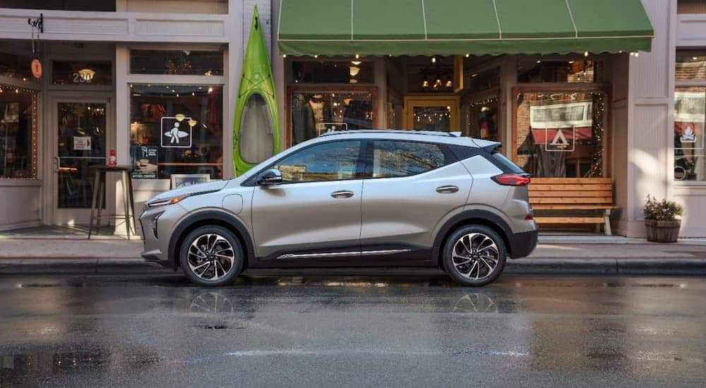 A sliver 2022 Chevy Bolt EUV is shown from the side while parked on a city street.