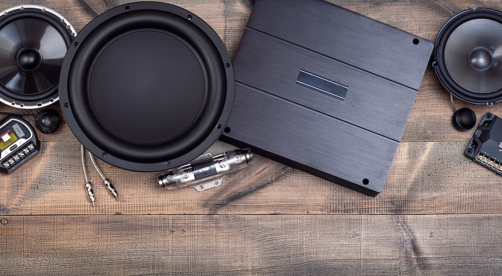 One of the most popular vehicle accessories, car audio equipment, is shown laid out on a wooden table.