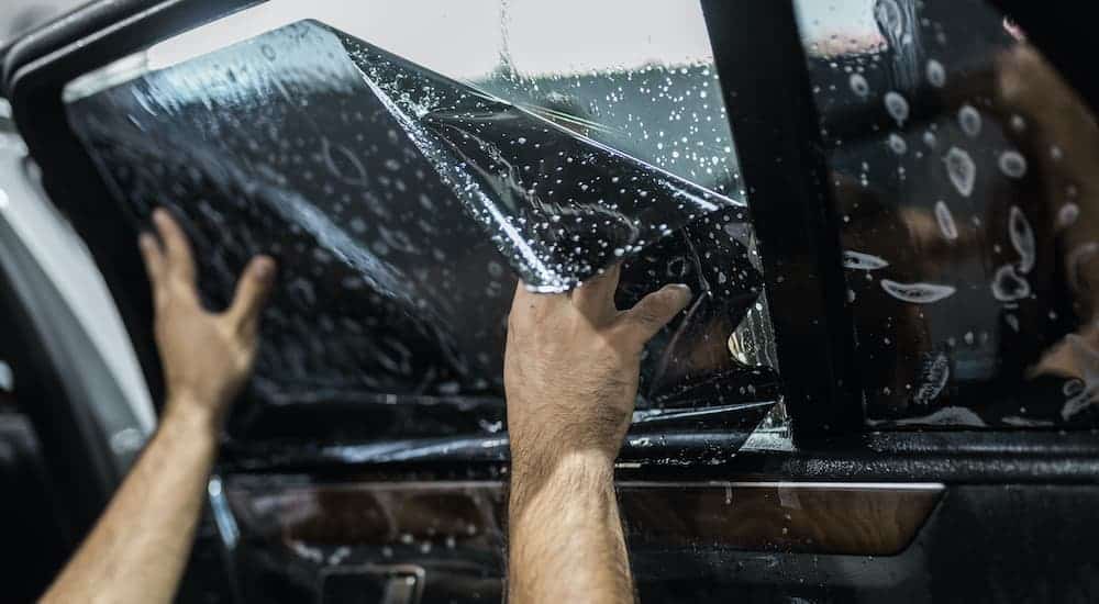 A close up shows window tint being installed on a vehicle.