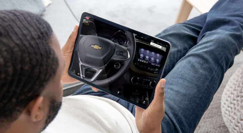 A man is looking at the steering wheel of a 2021 Chevy Blazer on a tablet.