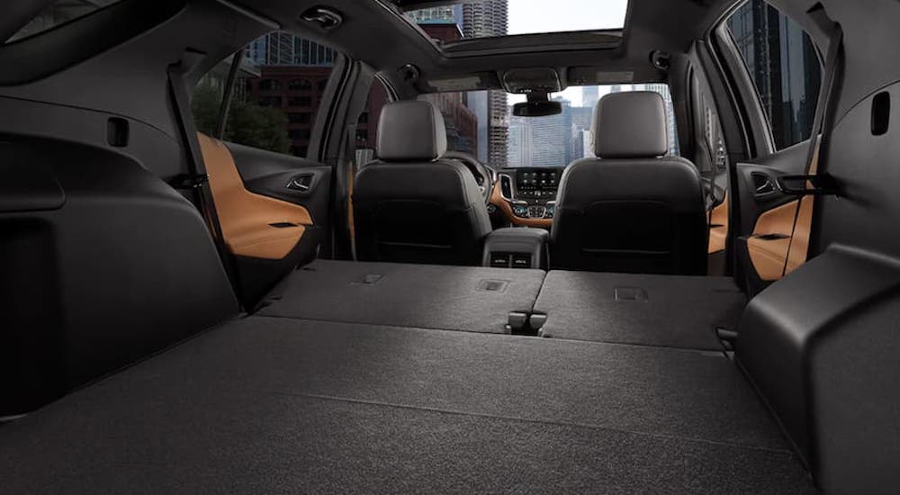 The black and tan interior in a 2021 Chevy Equinox shows the rear seats folded down.