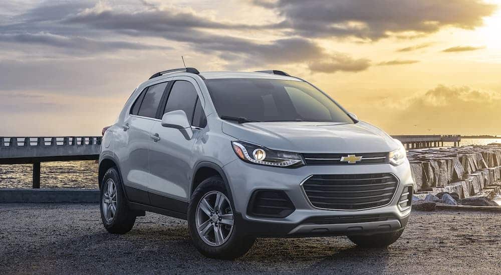 A silver 2021 Chevy Trax is parked in front of a pier at sunset.