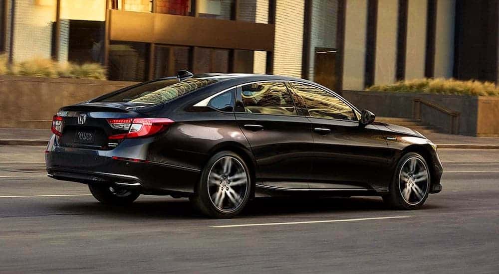 A black 2021 Honda Accord is shown from a rear angle driving on a city street after leaving a Honda Accord dealer.