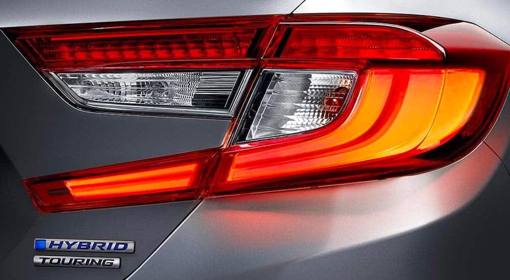 A closeup shows the taillight and Hybrid badging on a gray 2021 Honda Accord.